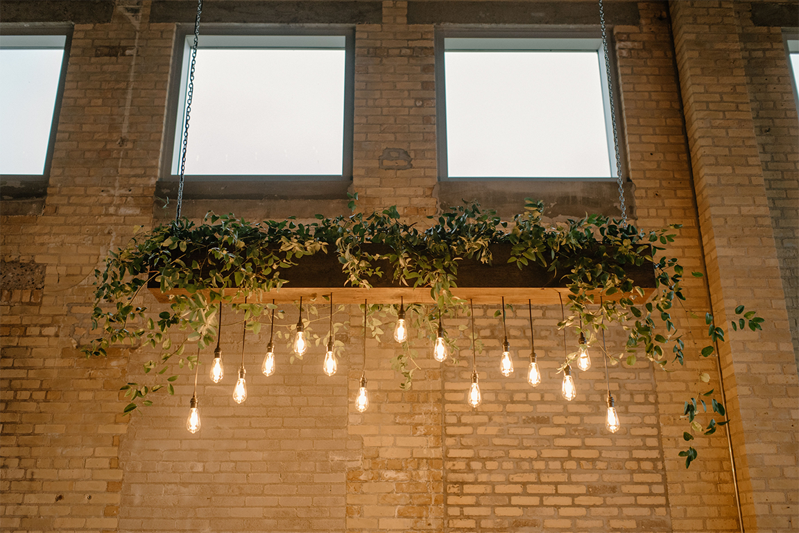 Hanging Edison bulbs and greenery on brick